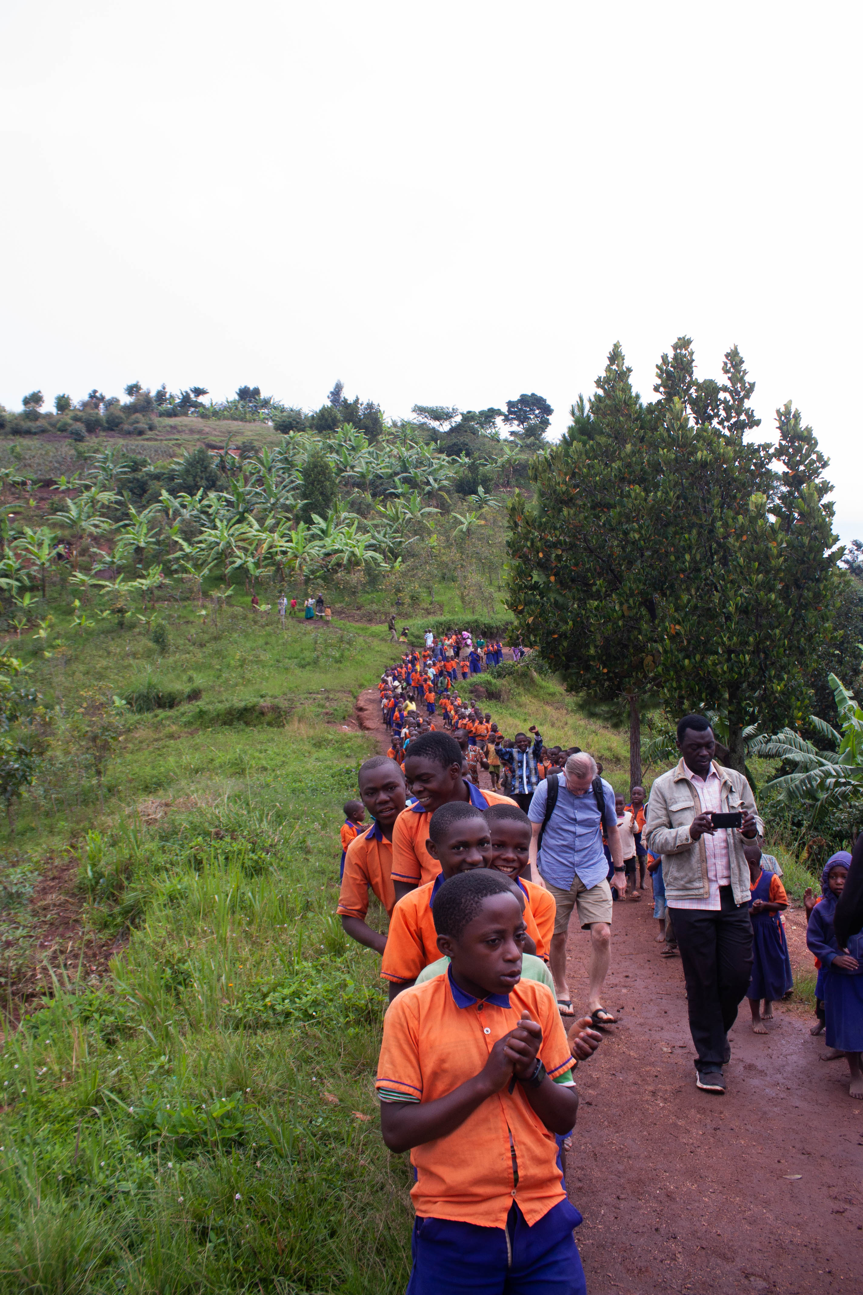 Am 4. Tag besuchte das Team die Matere Model School, die auf den Hügeln oberhalb von Kasese liegt. Auf dem Foto gehen die Schulkinder den unbefestigten Weg entlang und schließen sich dem Team an, um die Schule zu besuchen.