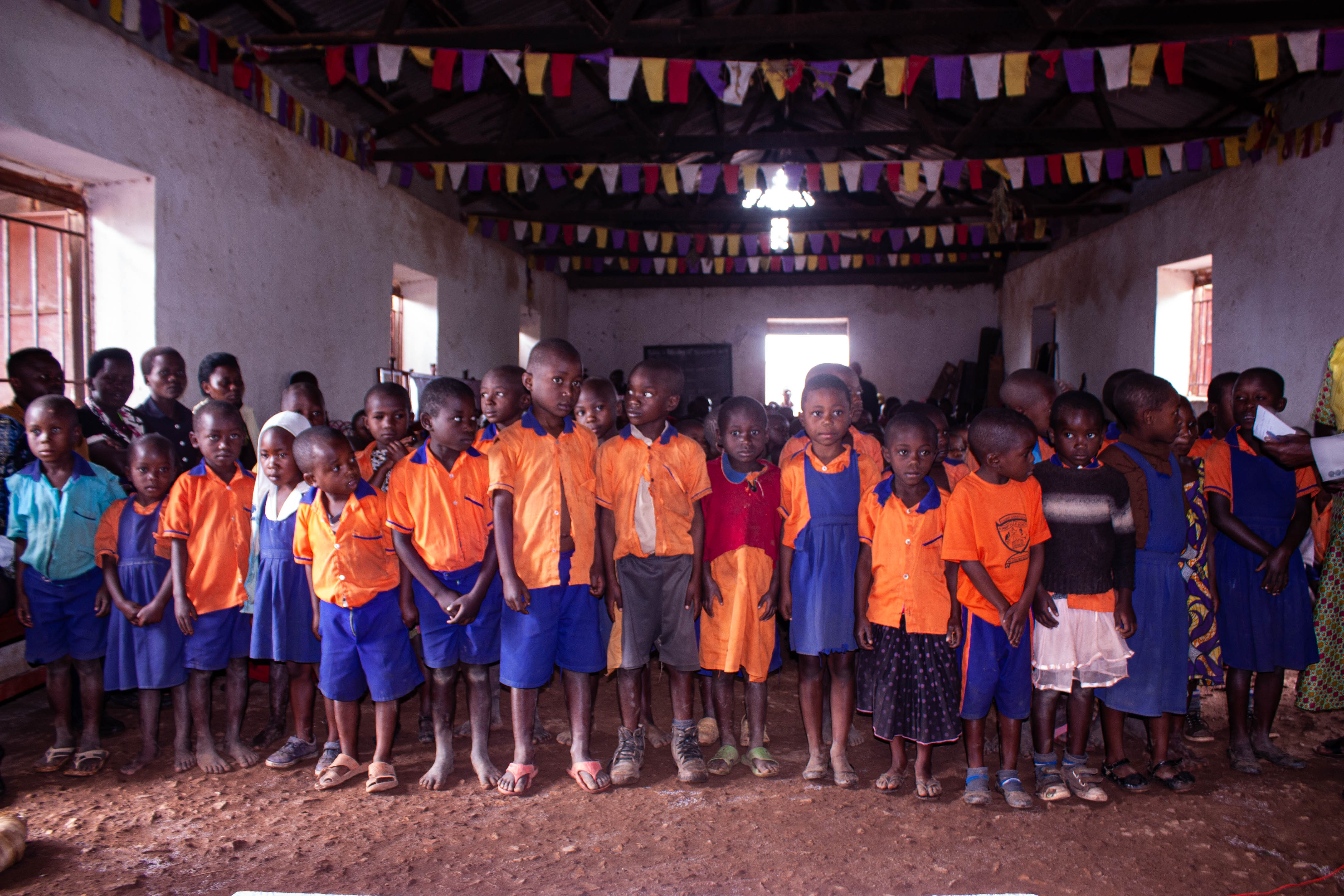 In der Matere Model School begrüßen die Kinder das Team mit Liedern und Tänzen. Hier haben sich die Kinder in einer Reihe aufgestellt, um mit der Begrüßungszeremonie zu beginnen.